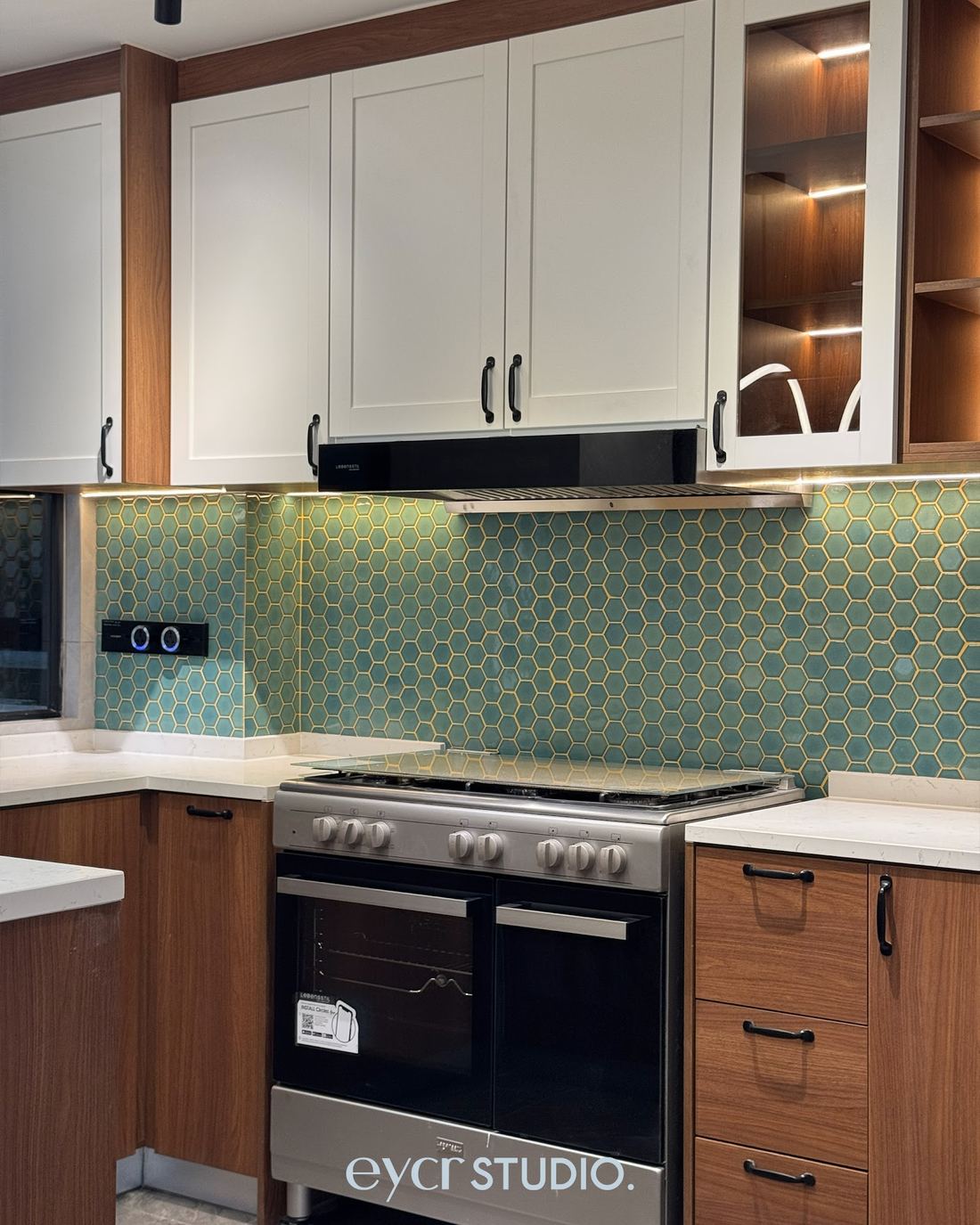 Kitchen with walnut cabinets and teal hexagon backsplash