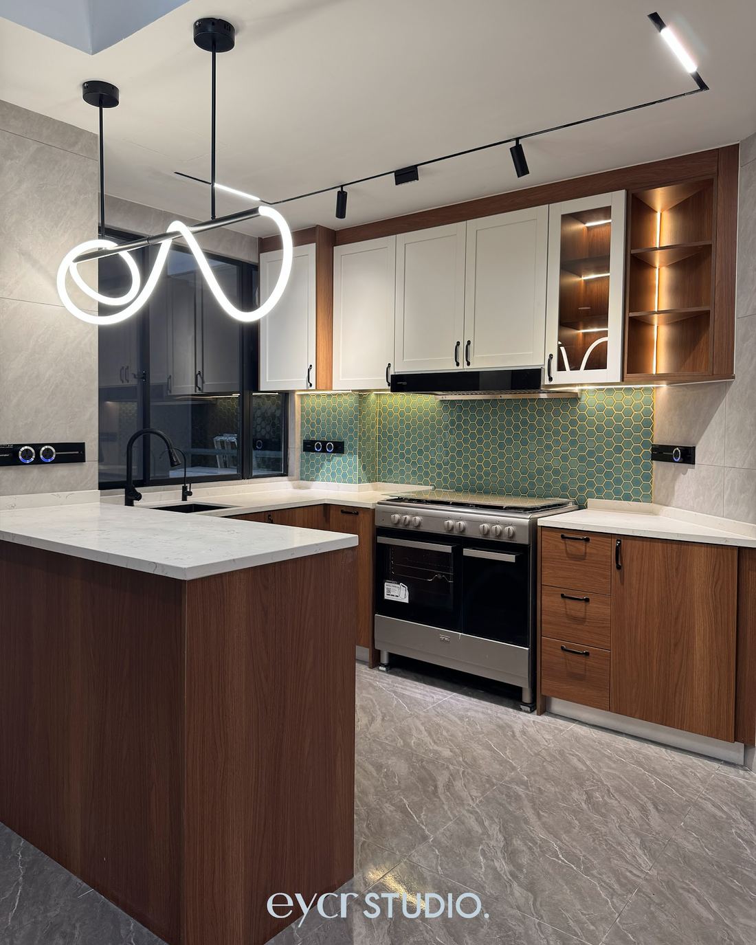Finished kitchen with walnut cabinets, teal hexagon backsplash and neon pendant